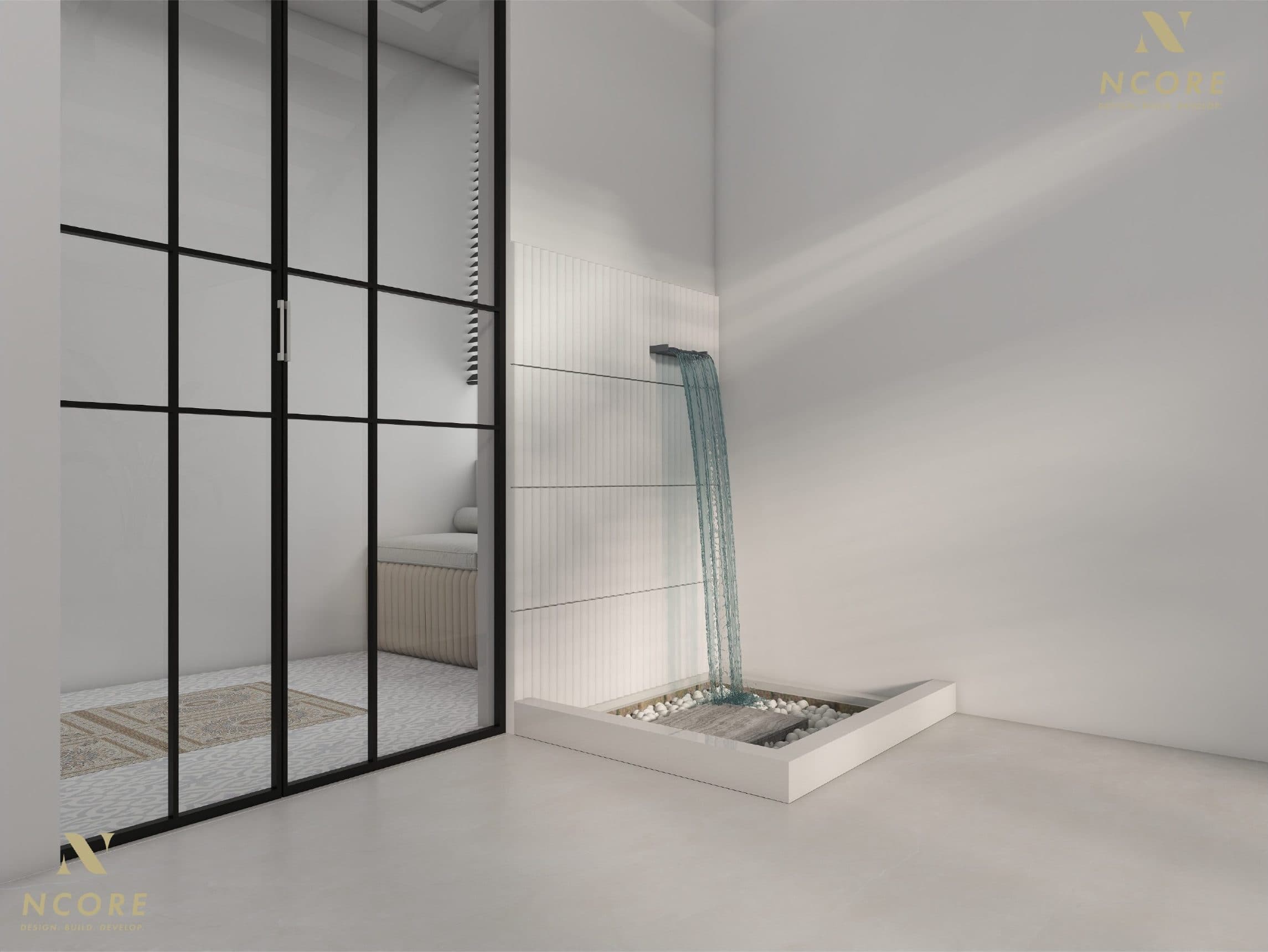 Internal court where a sheet of water falls onto a pebble bed beside black-framed glazed doors