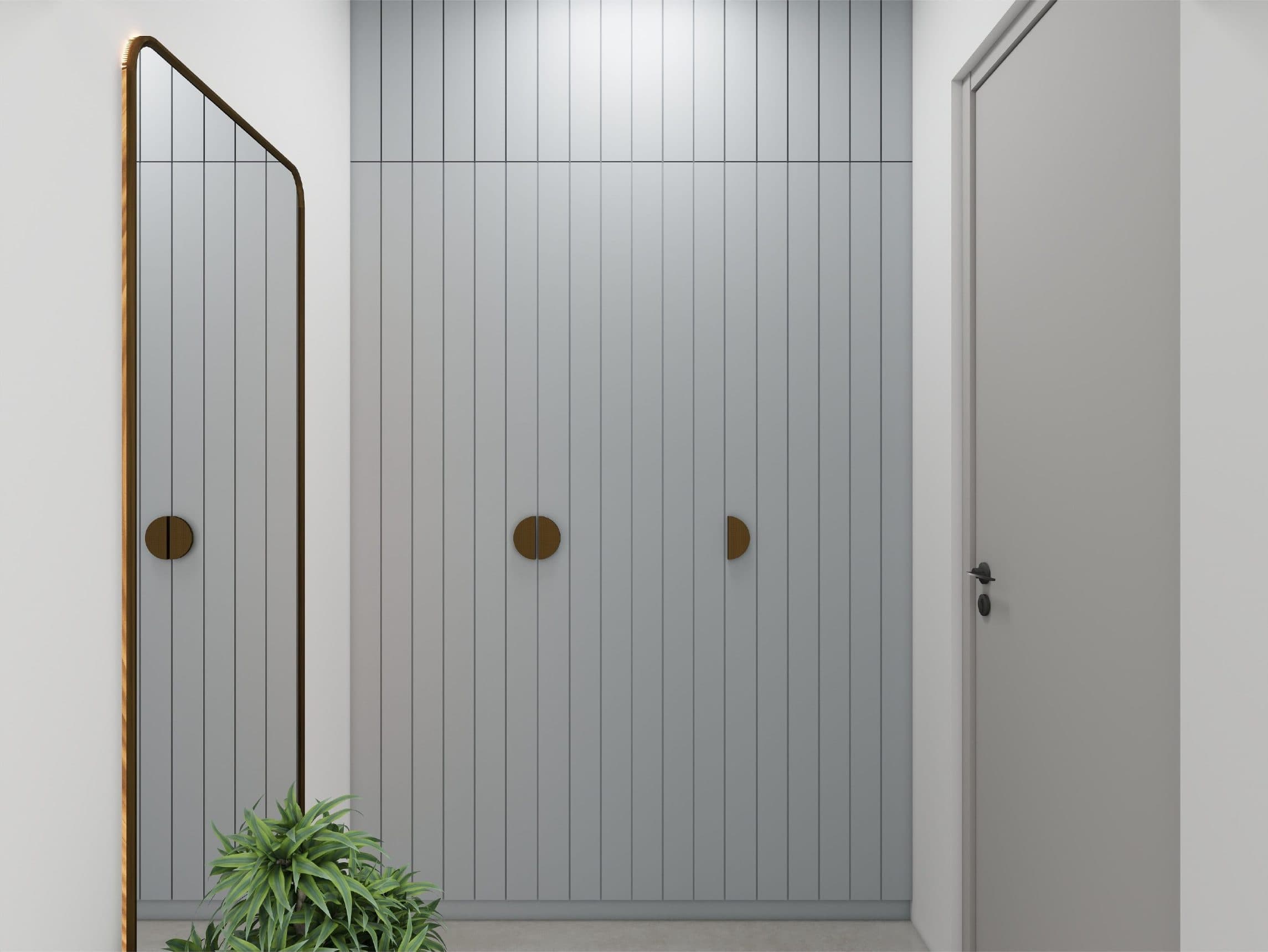 Fluted grey wardrobe fronts with circular brass pulls and a full-height brass-framed mirror